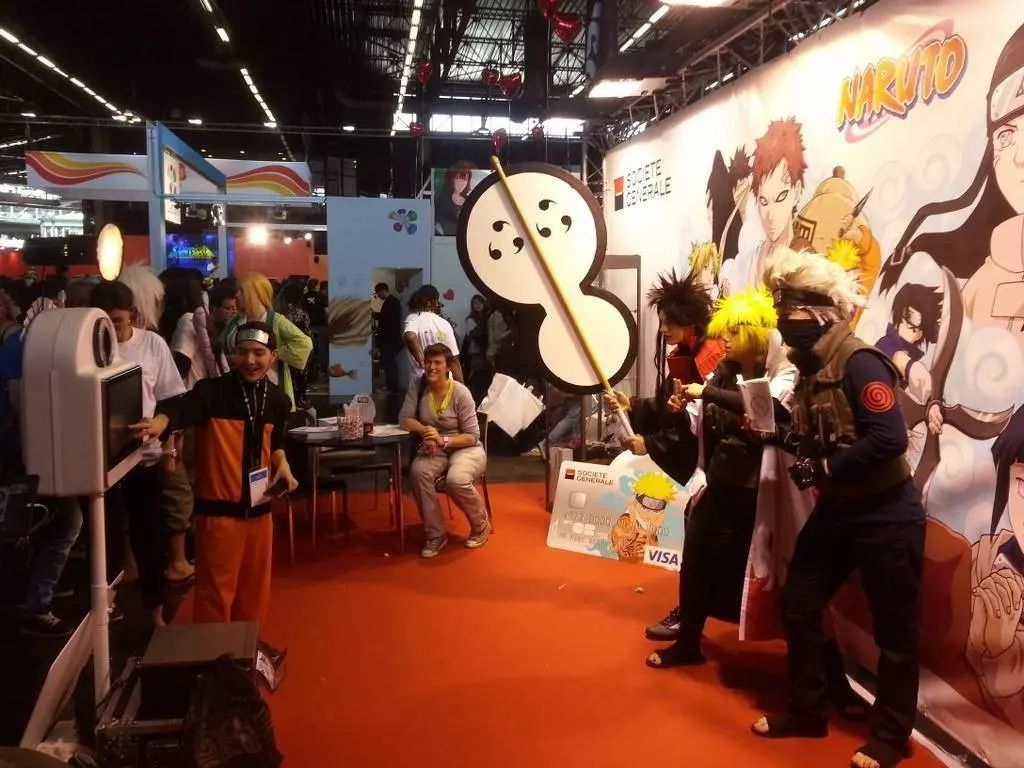 Cosplayers posant devant une fresque Naruto, borne photo à gauche, stand de la Japan Expo
