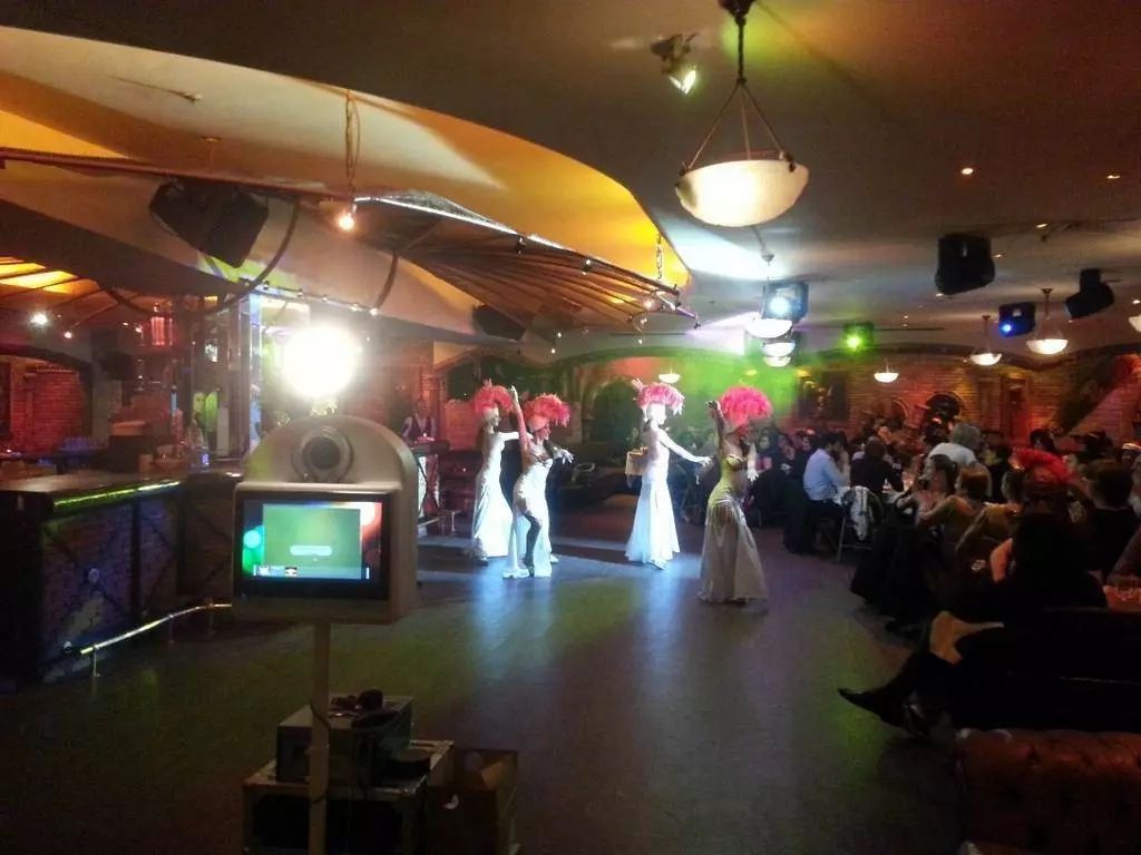 Borne photo dans un cabaret pendant le passage de danseuses en costume de plumes