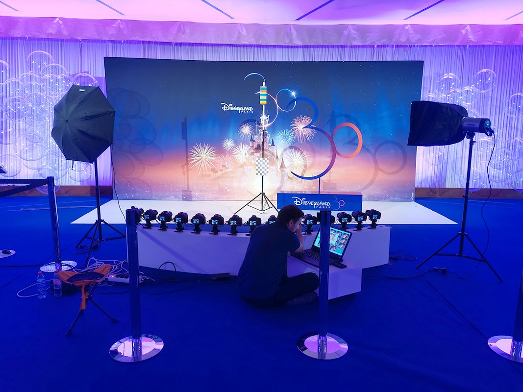 Technicien réglant l'arc de caméras devant un décor Disneyland Paris éclairé en bleu