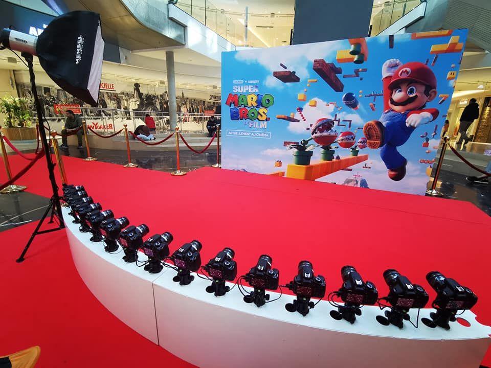 Arc blanc d'appareils photo devant l'affiche Super Mario Bros. sur tapis rouge