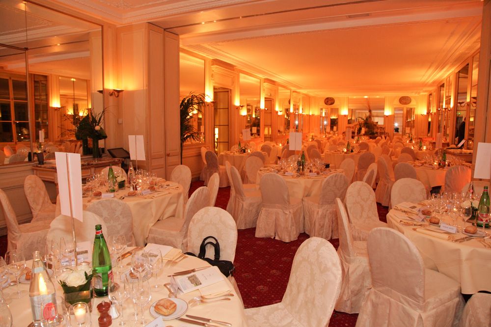 Salle de dîner aux tables rondes nappées de blanc, lumières chaudes