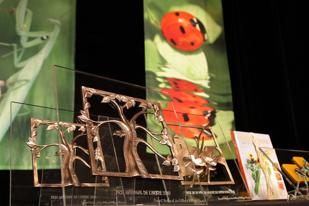 Trophées en métal découpé devant une grande coccinelle décorative, Villes et Villages Fleuris