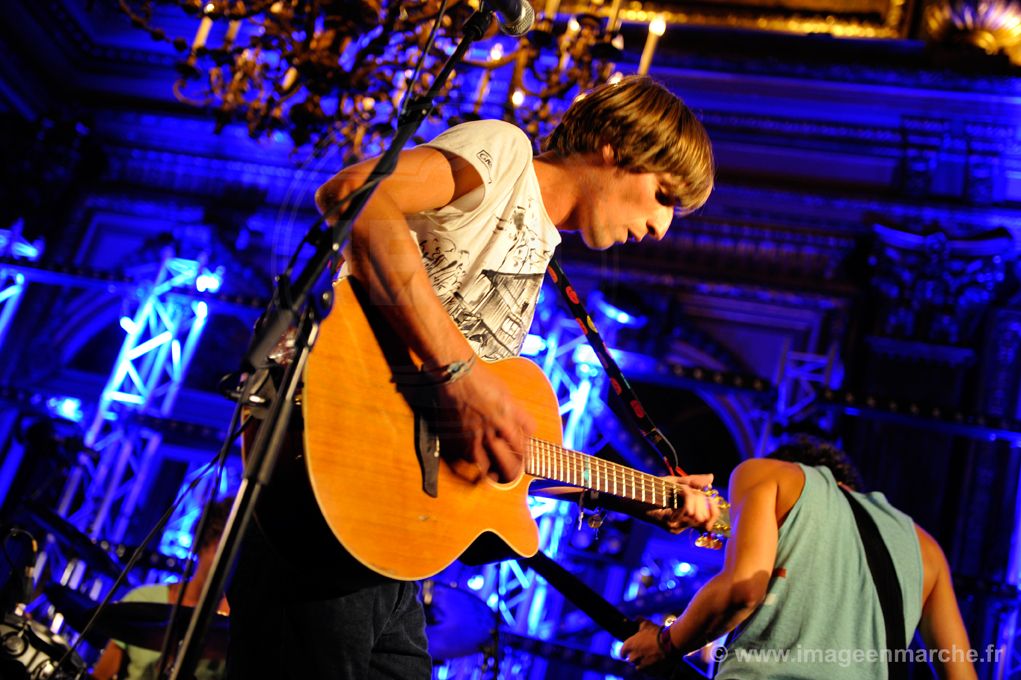 Guitariste à la guitare acoustique sous un projecteur bleu, salon doré