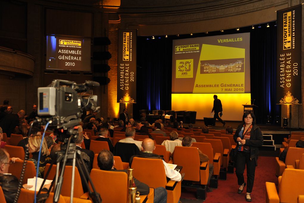 Assemblée générale 2010 avec caméra de captation au premier plan et écran géant jaune