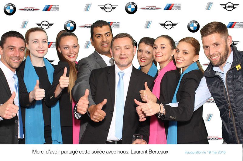 Équipe d'une dizaine de personnes pouces levés devant un mur aux logos BMW et MINI