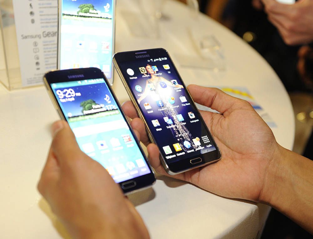 Deux mains tenant côte à côte deux Samsung Galaxy écrans allumés