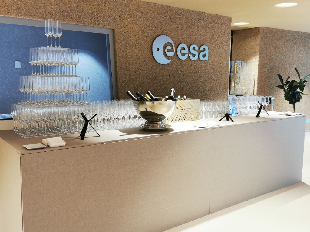 Bar de réception avec pyramide de coupes de champagne, logo ESA au mur