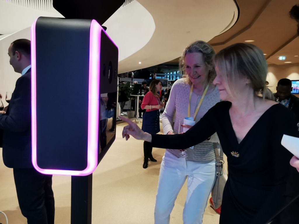 Deux invitées choisissant leur décor sur l'écran tactile de la borne