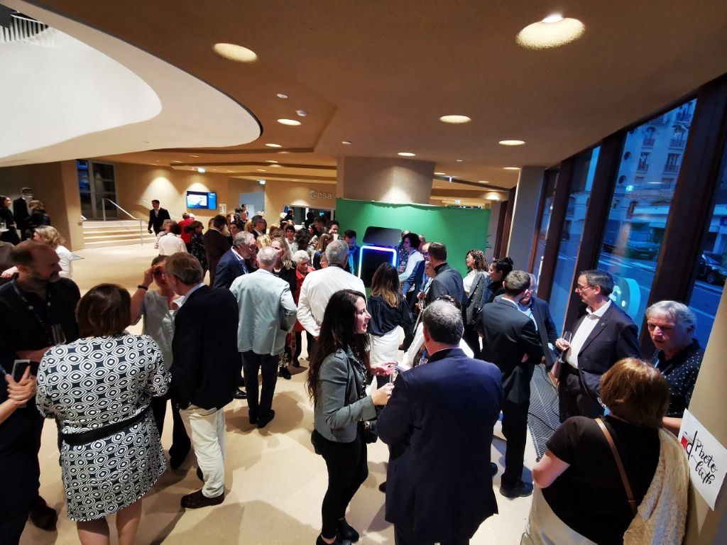 Hall rempli d'invités pendant la soirée d'inauguration, fond vert au fond