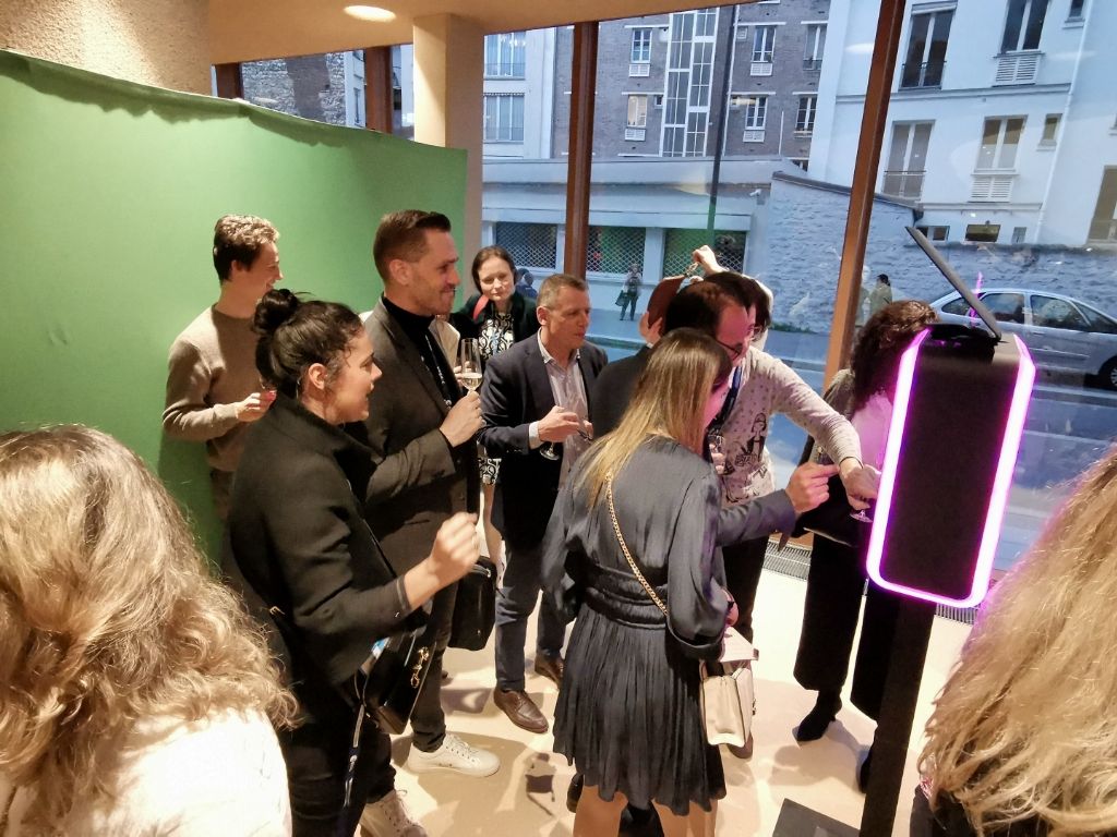 Invités se plaçant devant le fond vert, borne aux contours lumineux au premier plan