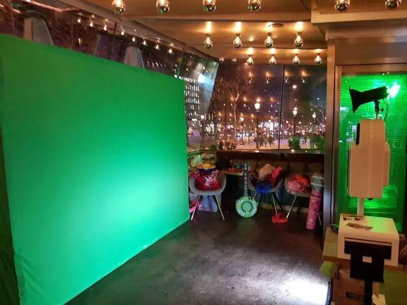 Grand fond vert éclairé dans un bar aux guirlandes lumineuses, borne photo à droite