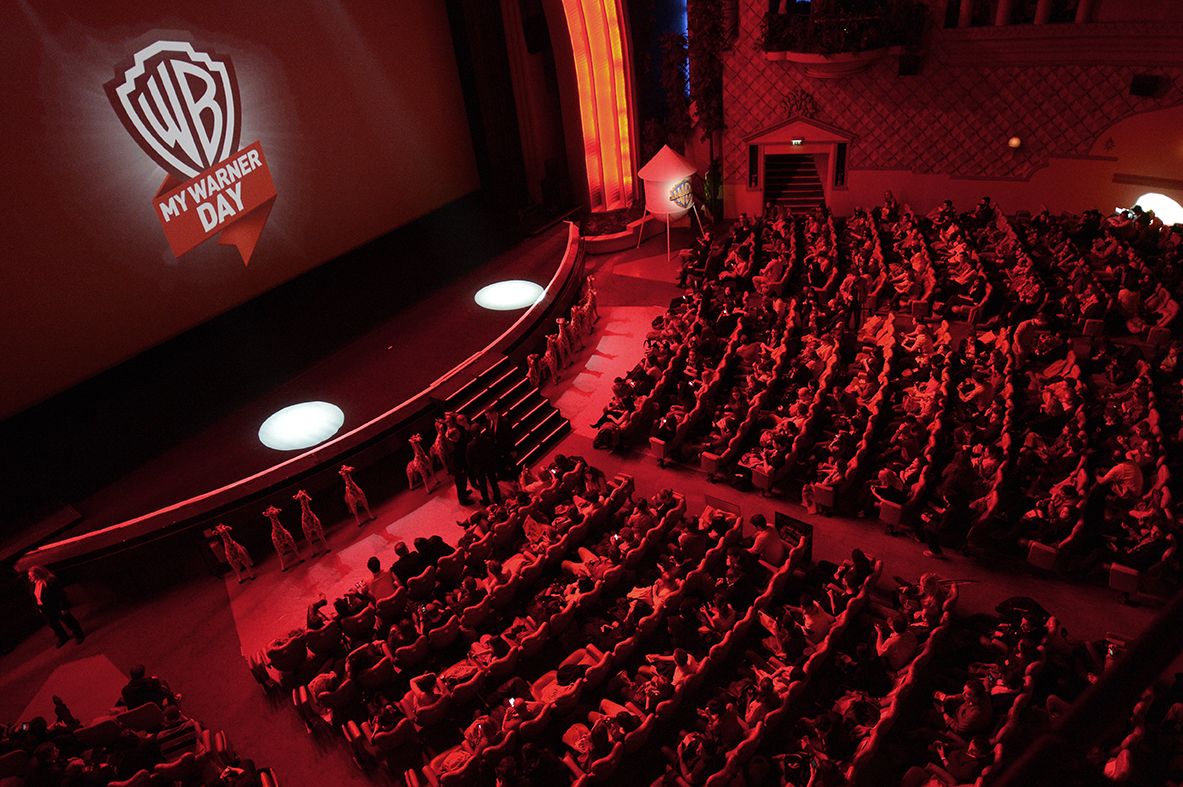 Salle de cinéma baignée de lumière rouge, logo My Warner Day sur l'écran