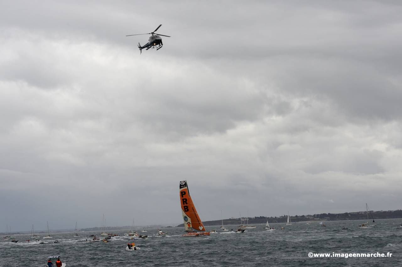 Hélicoptère de télévision au-dessus de la mer, voilier orange PRB à l'horizon