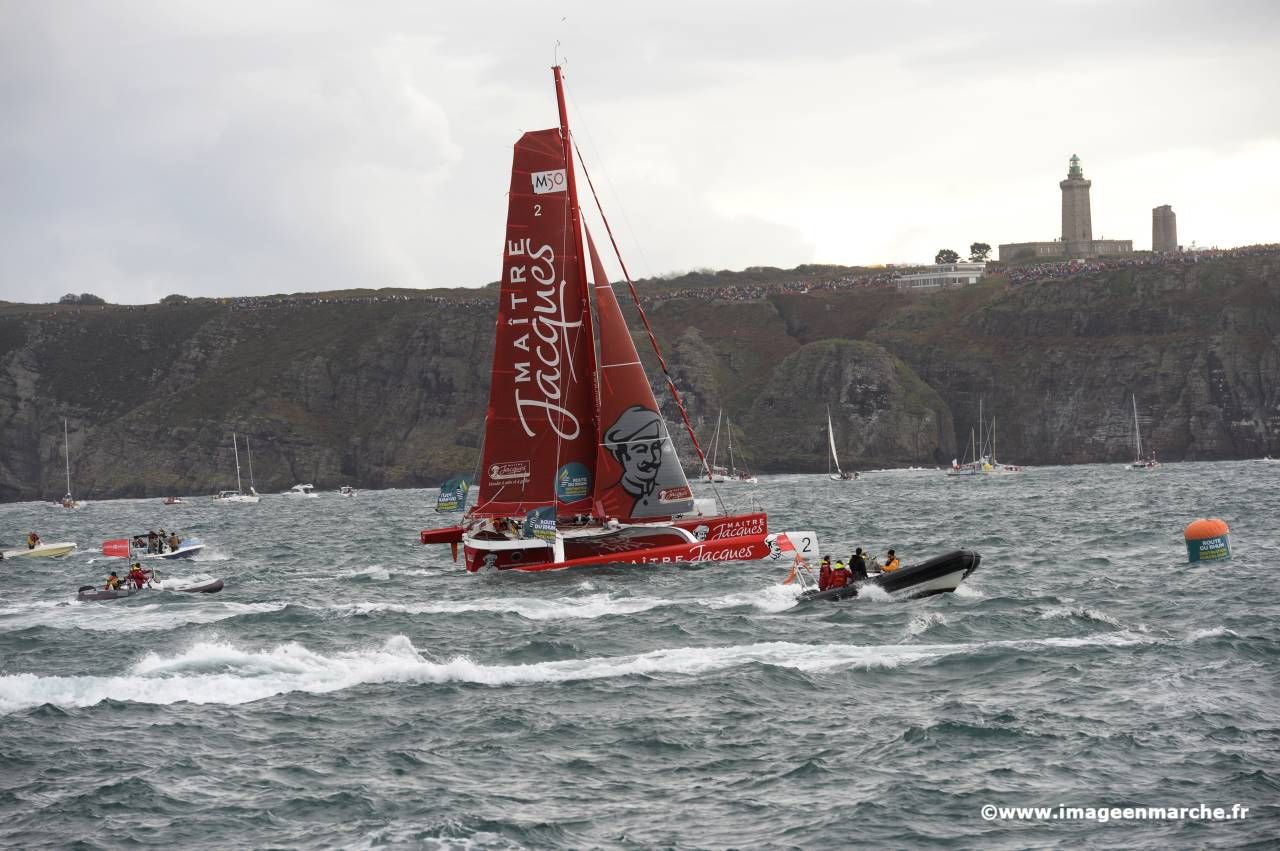 Trimaran rouge Maître Jacques au pied des falaises, sillage blanc
