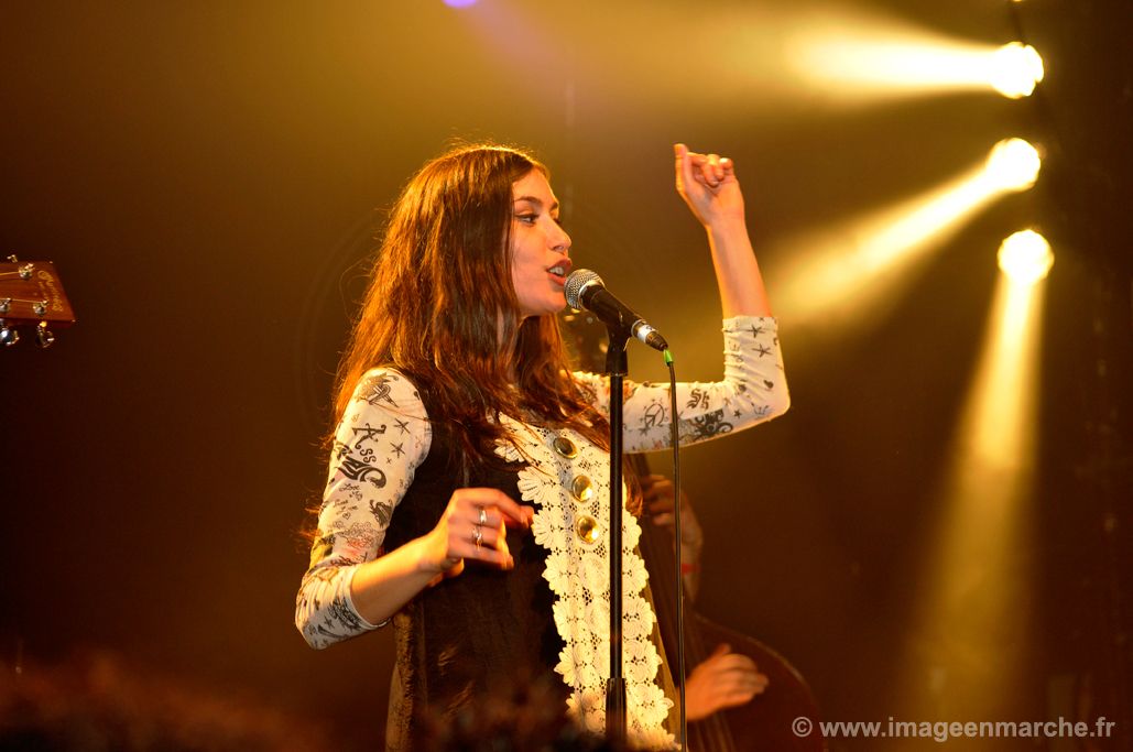 Olivia Ruiz au micro sous des projecteurs jaunes, tenue brodée