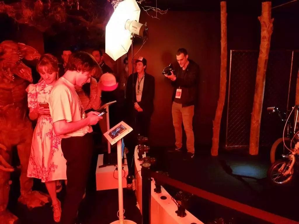Visiteurs consultant leur vidéo sur tablette dans le décor rouge Stranger Things, photographe en action